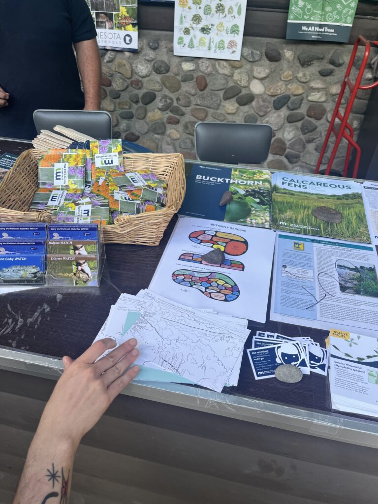 A hand reaching for a postcard on a state fair booth counter at the DNR building.