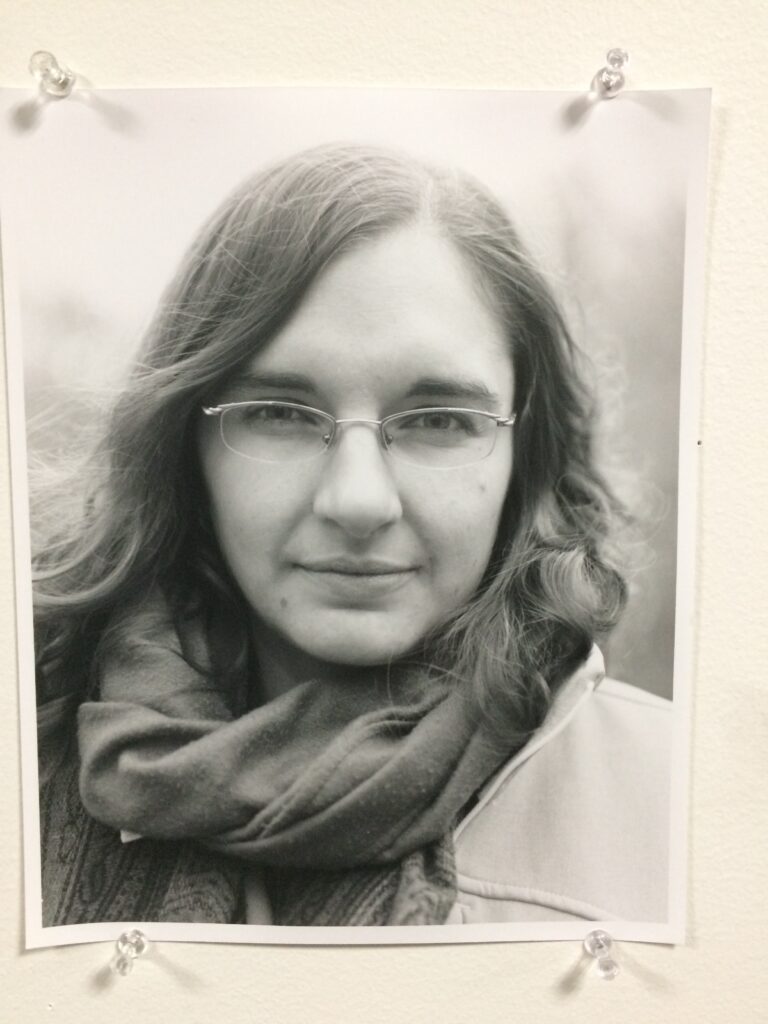 A black and white film photo headshot of a person pinned to a wall.