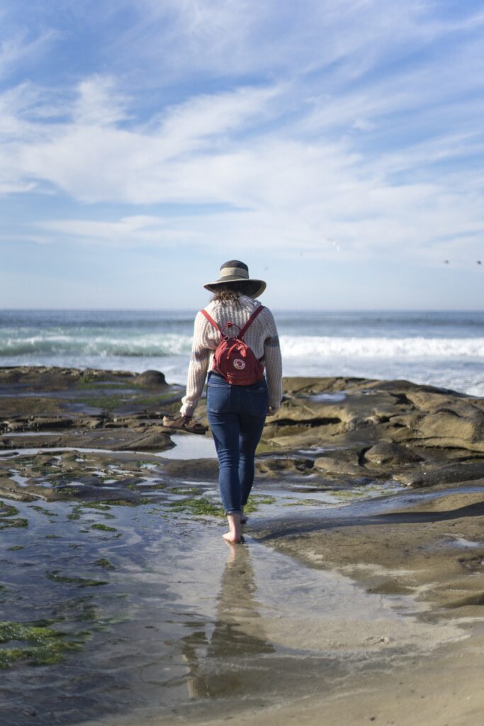 A person walking along a beach away from a camera.