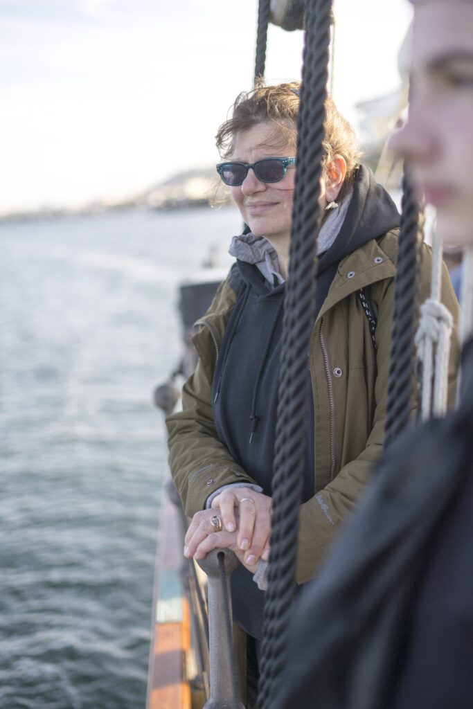 A person standing on the edge of a boat looking out to sea.