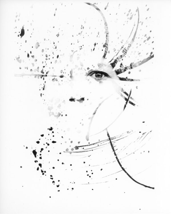 A portrait of a person where most of the image is obscured in white except where splattered liquid has revealed the image.